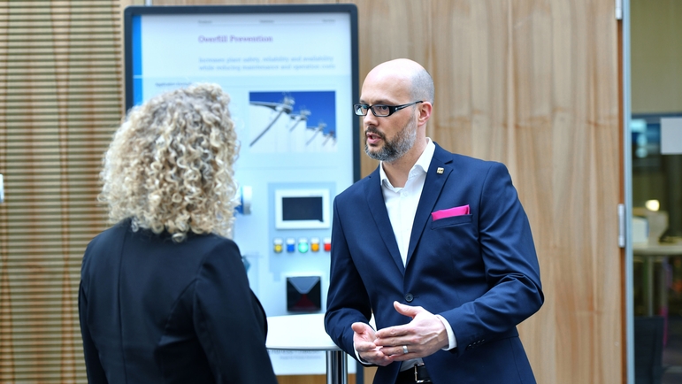 Empleado y cliente charlan delante de un expositor en un seminario