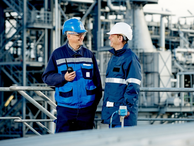 Dos ingenieros trabajan de pie en una refinería.